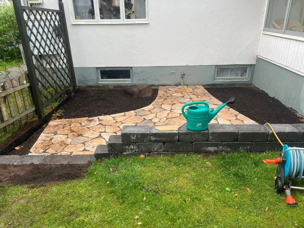 Gång av natursten i en rabatt, inramad av murblock